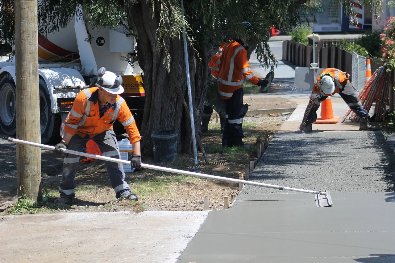 Crew screeding a freshly poured concrete sidewalk